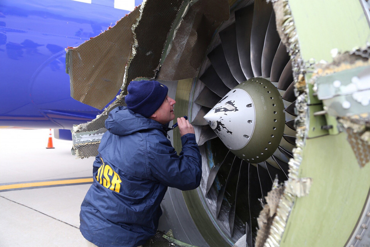 Philadelphia, 2018. április 18.
Az Amerikai Nemzeti Közlekedésbiztonsági Ügynökség által közreadott képen szakértő vizsgálja a Southwest Airlines 1380-as járatának felrobbant hajtóművét a Philadelphiai Repülőtéren 2018. április 17-én, miután a gép kényszerleszállást hajtott végre. A New Yorkból a dallasi Love Fieldbe tartó járat hajtóműve repülés közben robbant fel, a gép ablakai betörtek, a balesetben legkevesebb egy ember életét vesztette. (MTI/EPA/NTSB)