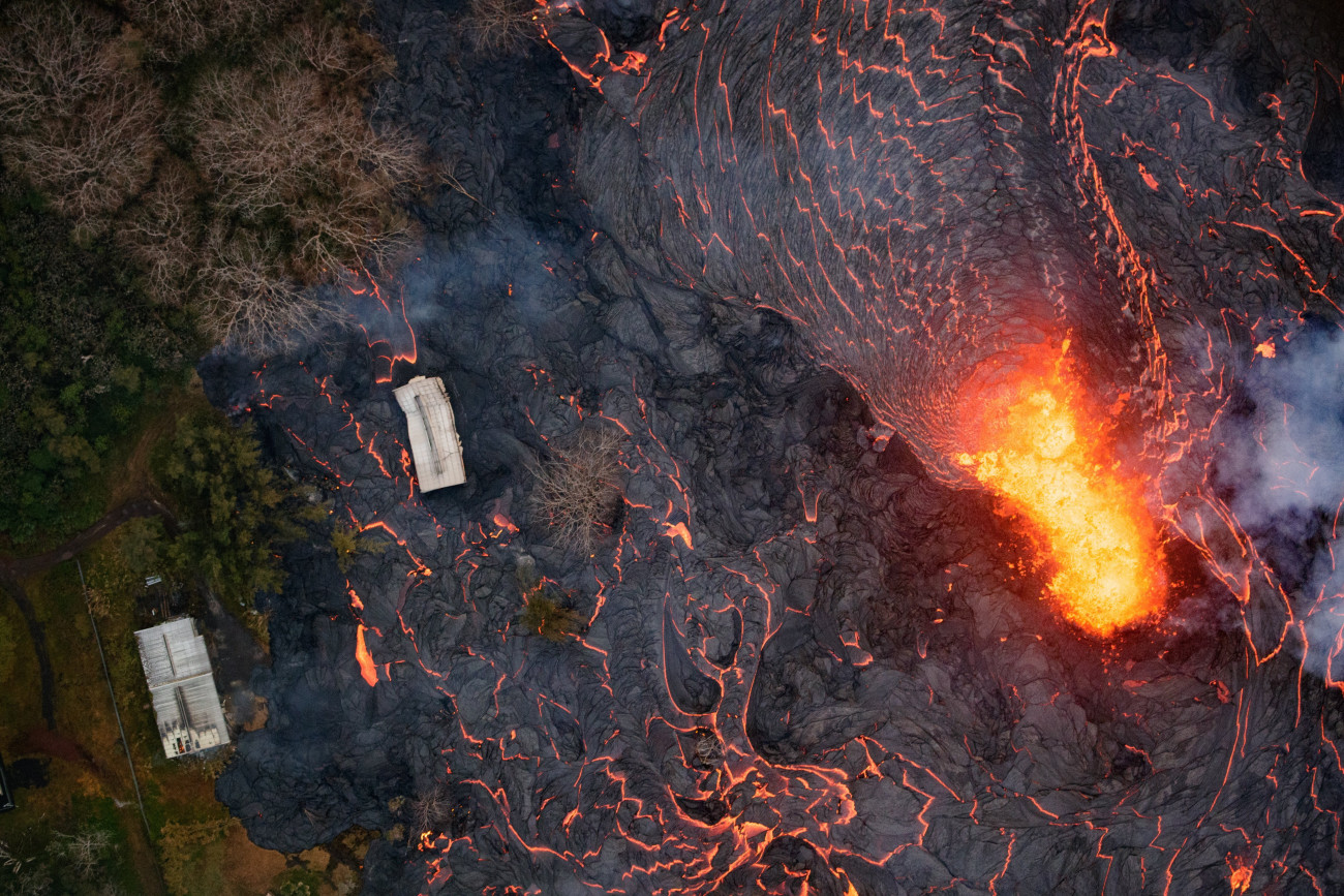 Pahoa, 2018. május 23.
Légi felvétel a Kilauea tűzhányó lávafolyamáról, amint felperzseli az útjában lévő növényzetet a hawaii nagy szigeten fekvő Pahoa város környékén 2018. május 22-én. A világ egyik legaktívabb tűzhányójának számító Kilauea vulkáni tevékenysége május 3. óta tart. A környékén kötelező kitelepítés van érvényben, a lávafolyam eddig 44 házat pusztított el. Jelenleg tilos az óceánban való fürdőzés a térségben, mert a láva és az óceánvíz találkozásakor veszélyes sósav keletkezhet, a vulkán pedig egyre nagyobb mértékben lövell ki szintén mérgező kén-dioxidot. (MTI/EPA/Paradise Helicopters/Bruce Omori)