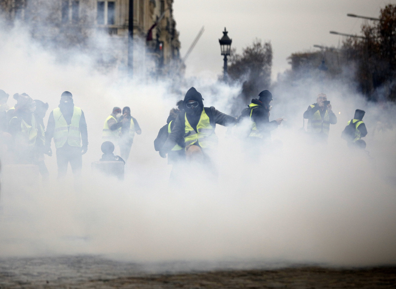 Párizs, 2018. december 1.
A dráguló üzemanyagárak ellen tiltakozó sárga láthatósági mellényt viselő tüntetők könnygázgránátok füstjében a rendőrökkel vívott összecsapás közben a párizsi Champs-Elysées sugárút közelében 2018. december 1-jén.
MTI/AP/Kamil Zihnioglu