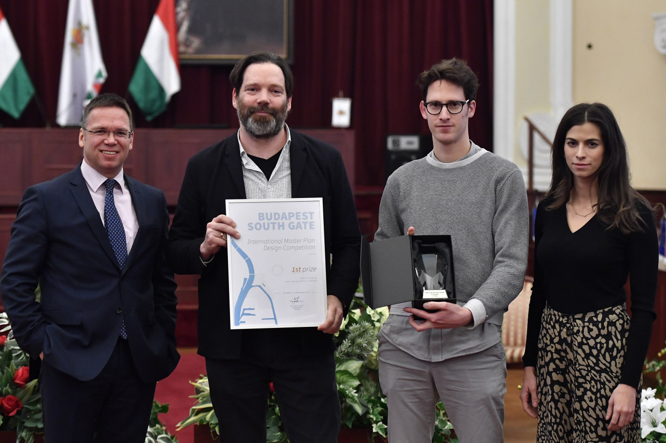 Budapest, 2018. december 19.
Szalay-Bobrovniczky Alexandra humán főpolgármester-helyettes, Fürjes Balázs, a Miniszterelnökség Budapest és a fővárosi agglomeráció fejlesztéséért felelős államtitkára, a bírálóbizottság elnöke (b) valamint Patrick Lüth, a győztes Snohetta Innsbruck tervezőiroda vezetője (b2) és munkatársa, Thomas Tait (j2) a Budapest Déli Városkapu nemzetközi tervpályázat eredményhirdetésén a Budapesti Városháza dísztermében 2018. december 19-én. A Duna, a Rákóczi híd, a Könyves Kálmán körút, a Soroksári út és a Weiss Manfréd út által határolt, mintegy 135 hektáros területen 12 ezer egyetemi hallgatónak szánt diákváros, valamint nemzetközi rangadók megrendezésére alkalmas sportlétesítmények épülnek.
MTI/-