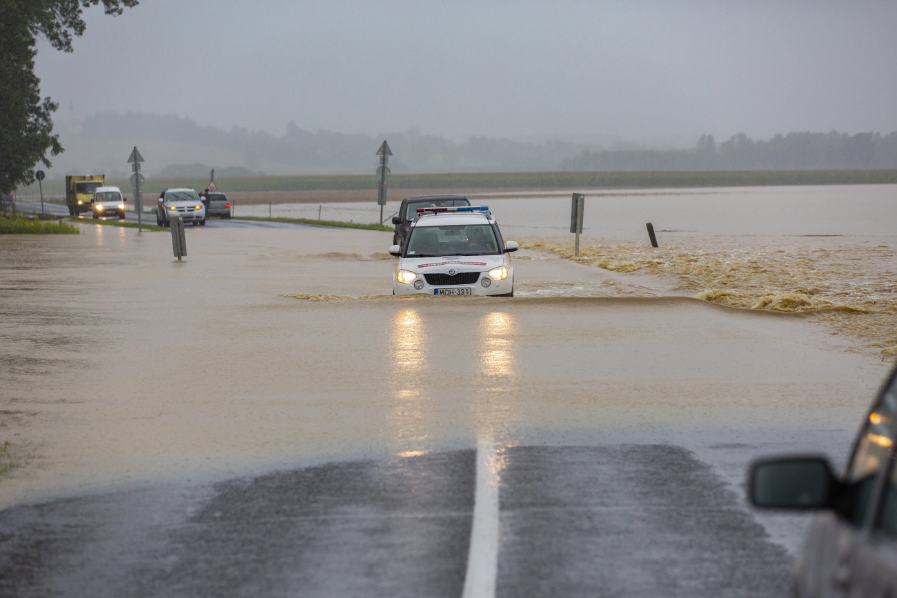 A katasztrófavédelm gépjárműve és egy terepjáró halad a nagy esőzés miatt vízzel elárasztott Csurgót és Gyékényest összekötő úton, a Somogy megyei Porrogszentkirály közelében 2020. július 25-én.
MTI/Varga György