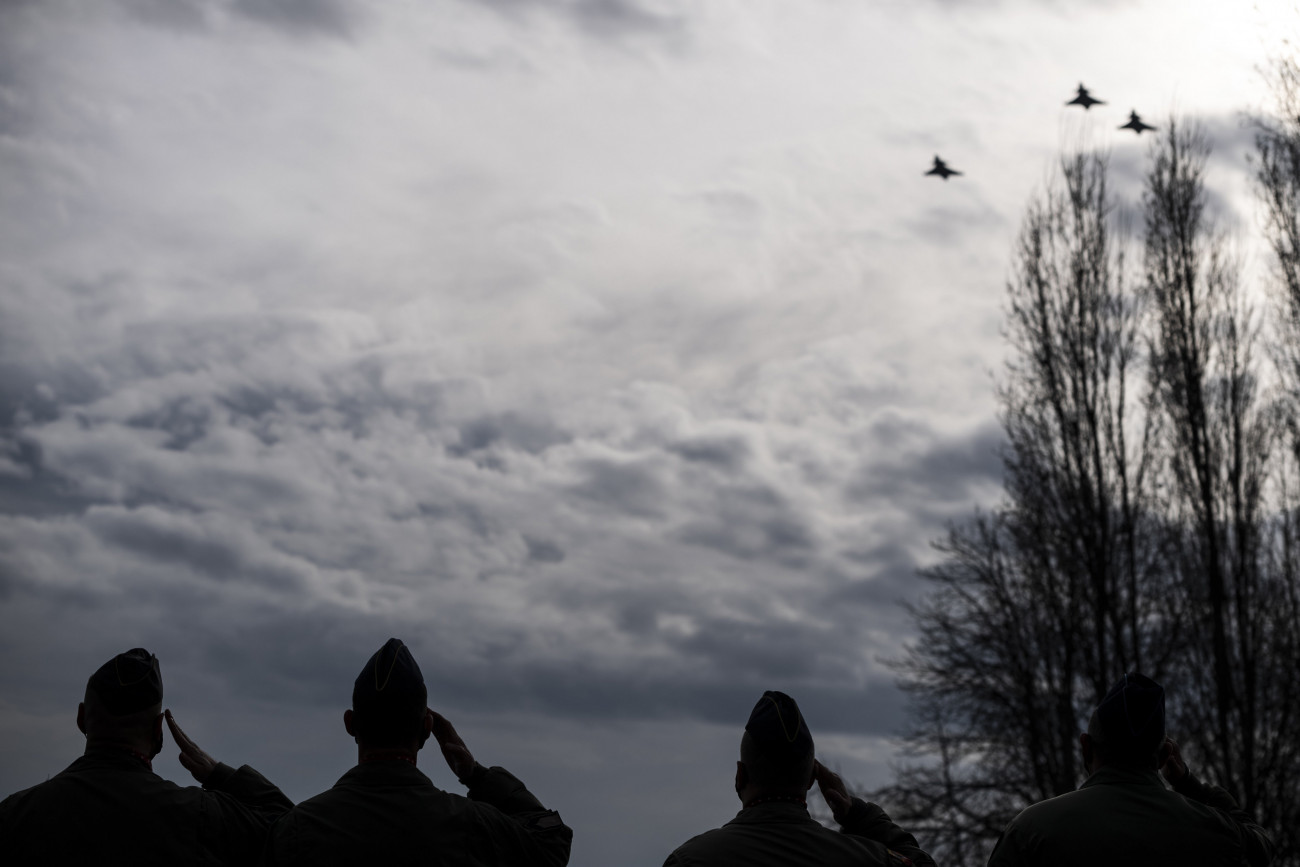 Budapest, 2021. január 23.
A Magyar Honvédség Gripen vadászrepülőgépei díszelgő kötelékrepüléssel búcsúznak a 97 esztendős korában elhunyt Frankó Endre nyugállományú főhadnagytól, a 101. Puma Honi Légvédelmi Vadászrepülő Osztály utolsó, még légiharcban is bevetett pilótájától a Duna fővárosi szakasza felett, előtérben katonák tisztelegnek a III. kerületi Szent XXIII. János pápa parkban 2021. január 23-án. Frankó Endrét ezen a napon megtartott gyászszertartáson búcsúztatták és temették el az az Óbudai Jó Pásztor templomban.
MTI/Mónus Márton
