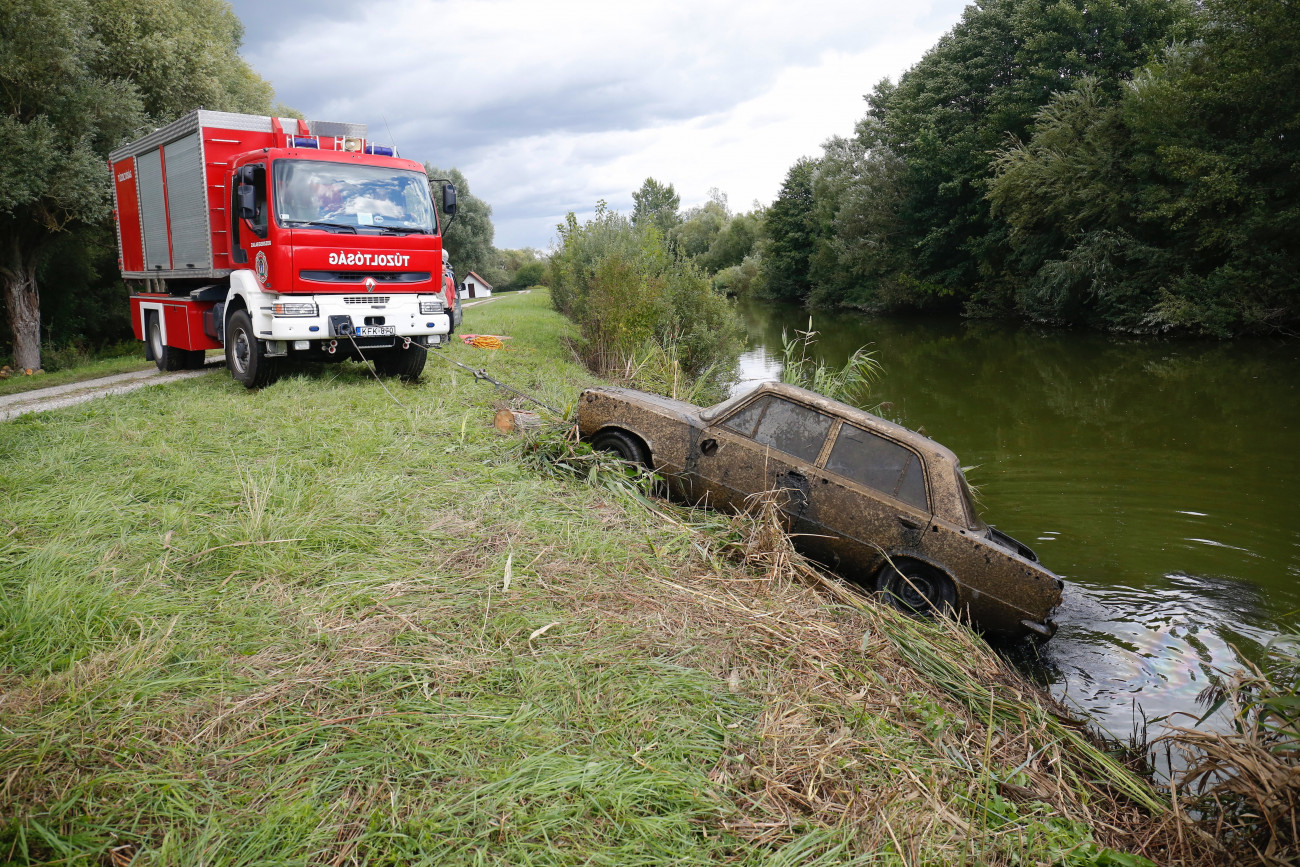 Zalavár, 2021. augusztus 31.
Tűzoltók kiemelnek egy autót a Zala folyóból Zalavár közelében 2021. augusztus 31-én. A vízből kiemelt Lada vélhetően egy az 1990-es évek vége felé ellopott autó, amiben a kiemelésekor nem találtak emberi maradványokat.
MTI/Varga György