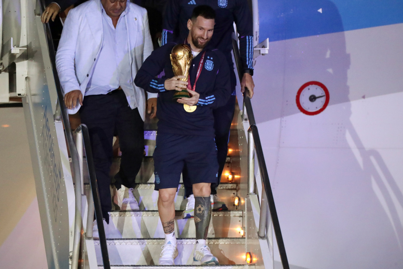 Buenos Aires, 2022. december 20.
Lionel Messi argentin csapatkapitány kezében a bajnoki trófeával, miután a válogatott játékosaival megérkezett a Buenos Aires-i Ezeiza repülőtérre 2022. december 20-án. Argentína két nappal korábban 4-2-re győzött a katari labdarúgó-világbajnokság döntőjében játszott Argentína-Franciaország mérkőzés 3-3-as hosszabbítása utáni tizenegyes-párbajban.
MTI/EPA/EFE/Raul Martinez