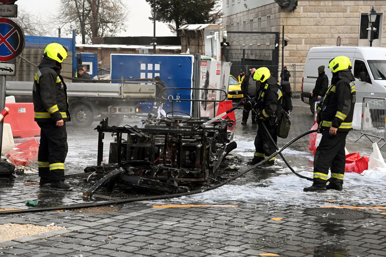 Budapest, 2023. december 11.
Kiégett elektromos városnéző kisbusz oltásának utómunkálatain dolgoznak tűzoltók a főváros I. kerületében, a budavári Dísz téren 2023. december 11-én.
MTI/Mihádák Zoltán