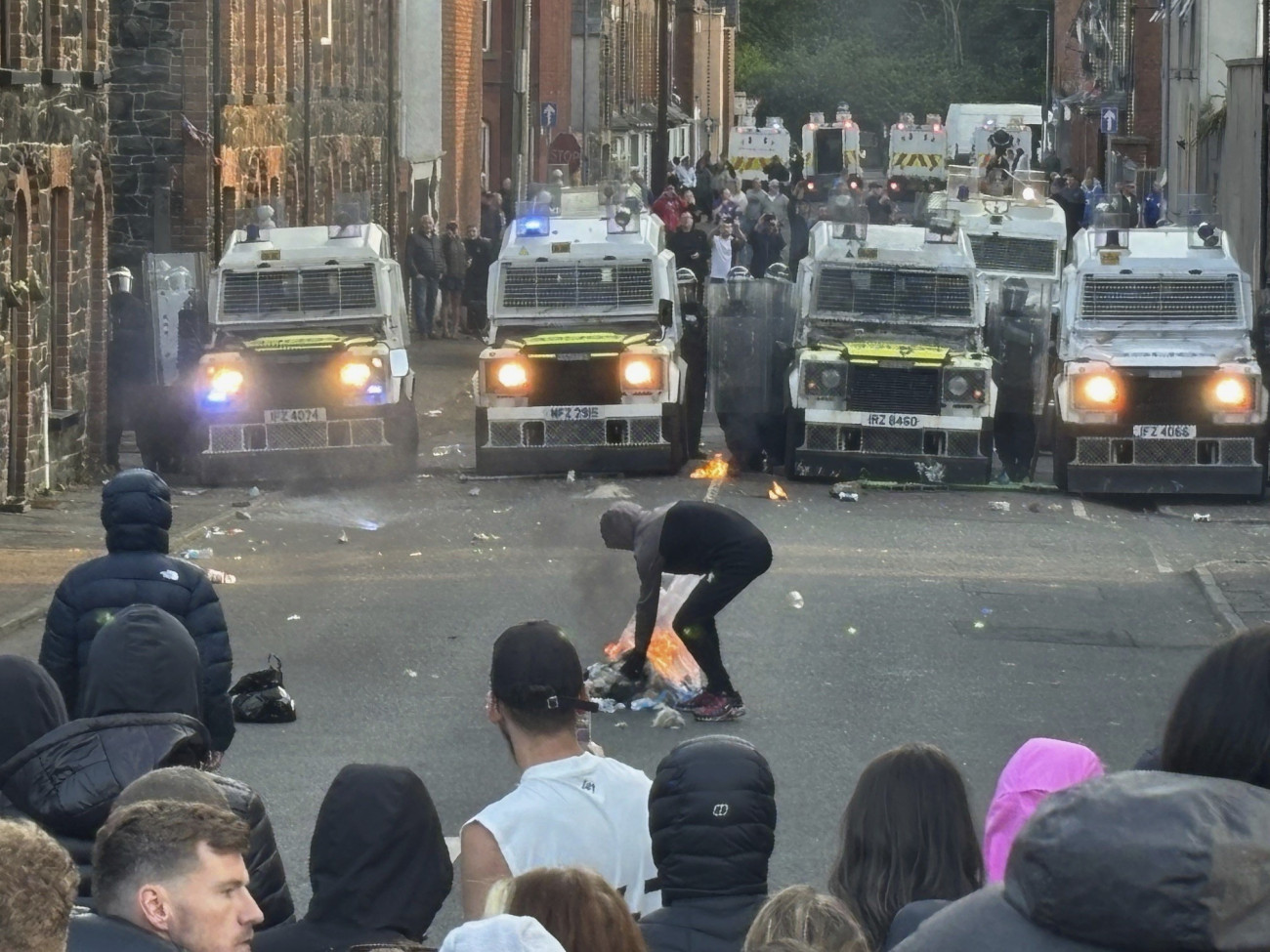 Ballymena, 2025. június 11.
Rohamrendőrök kisteherautókkal zárnak le egy utcát az észak-írországi Ballymena városában, ahol zavargások törtek ki egy bevándorlók által elkövetett szexuális támadás miatt 2025. június 10-én. Az indulatok azt követően szabadultak el, hogy két 14 éves román bevándorló fiatal megpróbált megerőszakolni egy helyi lányt.
MTI/AP/PA/Niall Carson