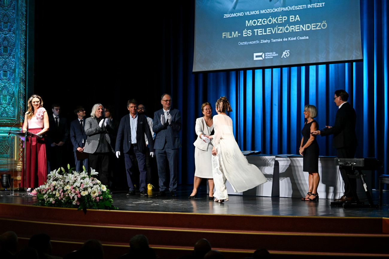 Budapest, 2025. július 15.
Sepsi Enikő, az SZFE rektora (j4) oklevelet ad át egy végzős hallgatónak a Színház- és Filmművészeti Egyetem (SZFE) tanévzáró és oklevélátadó ünnepségen az Uránia Nemzeti Filmszínházban 2025. július 15-én. Mellette Káel Csaba, a Nemzeti Filmintézet vezérigazgatója (j5) és Pacskovszky József, az SZFE Zsigmond Vilmos Mozgóképművészeti Intézet intézetvezető-helyettese (j6) és Zilahy Tamás dokumentumfilm-rendező (j7).
MTI/Purger Tamás