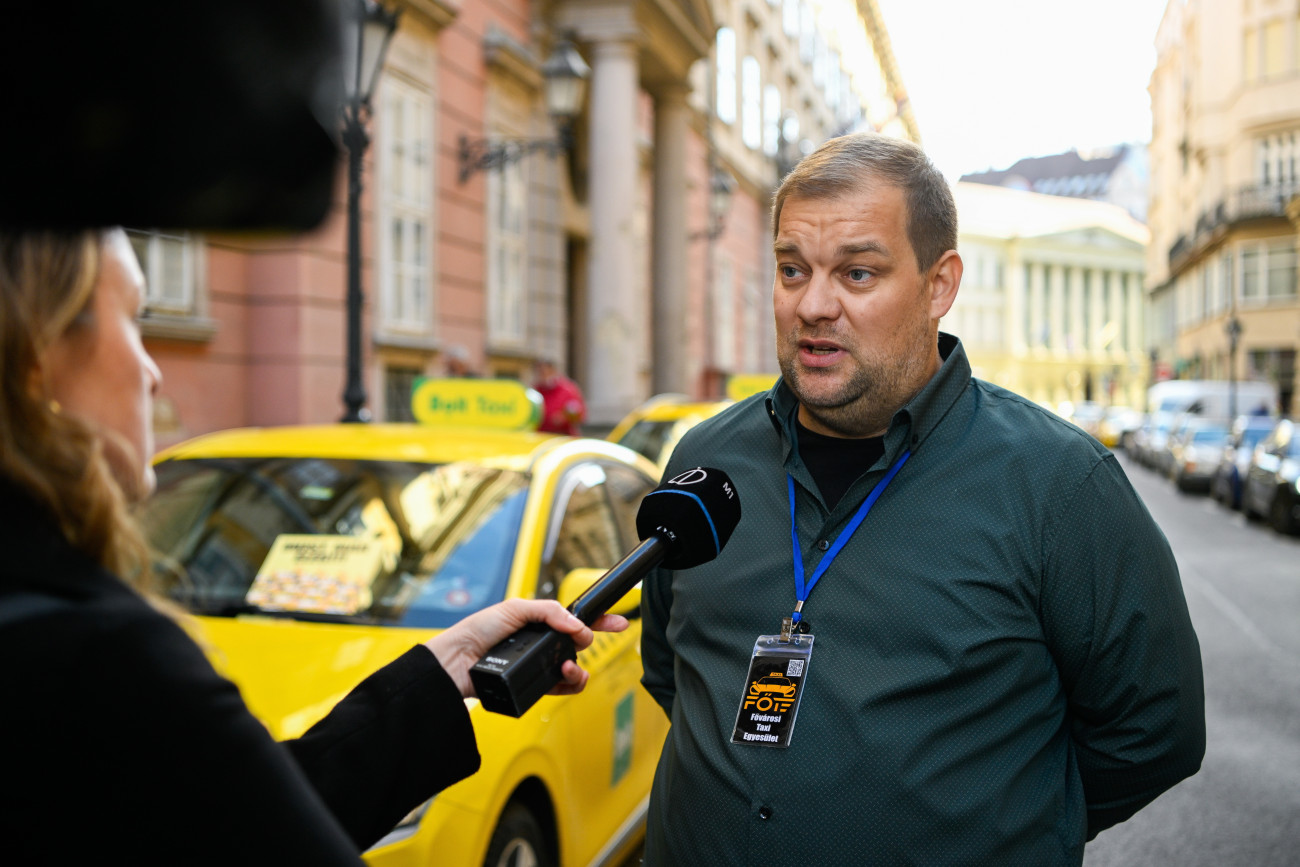 Budapest, 2025. október 29.
Váczi Norbert, a Fõvárosi taxi egyesület társelnöke nyilatkozik a sajtó képviselõinek taxisok tüntetésén a Fõvárosi Közgyûlés ülése alatt Városháza elõtt 2025. október 29-én. A taxisok tarifaemelést követelnek, valamint egyebek mellett szorgalmazzák az engedélyek számának korlátozását, az illegális fuvarszervezés felszámolását.
MTI/Purger Tamás