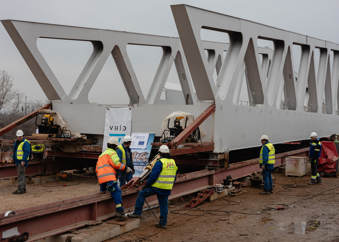 Budapest, 2026. január 28.
A Gubacsi úti második új vasúti hídját tolják végleges helyére a V-Híd szakemberei hidraulikus tolóberendezések segítségével a Kelenföld és Ferencváros közötti vasútvonal kapacitásbõvítésének a Déli Körvasút kialakítása második üteméhez kapcsolódó építési munkálatai során 2026. január 28-án.
MTI/Hatházi Tamás