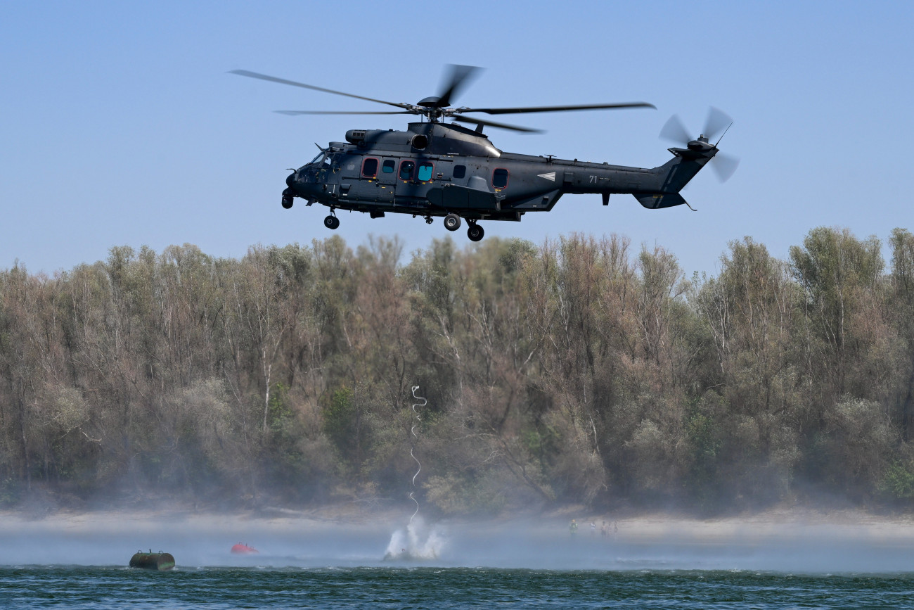 Paks, 2026. augusztus 15.
Betonkockát emel a Dunába a honvédség Airbus H225M típusú helikoptere a fenékküszöb építésének munkálatai során az MVM Paksi Atomerõmû közelében 2026. augusztus 15-én. Megkezdõdött a bárkák irányított süllyesztése Paksnál az atomerõmû mûködésének fenntartásához szükséges dunai vízszint emelése érdekében.
MTI/Bodnár Boglárka