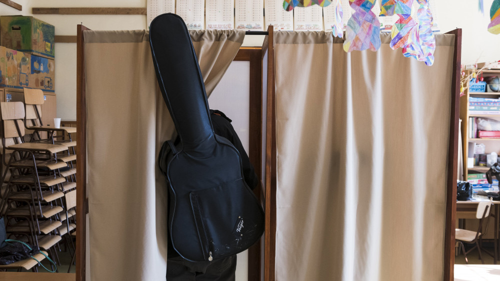 Egy szavazó gitárral a hátán Újbudán, a Bocskai István Általános Iskolában 2018. április 8-án. Az országban itt a legmagasabb, 10764 a szavazásra átjelentkezők száma.
