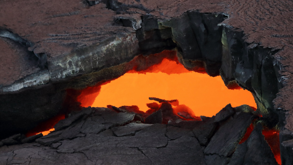Pahoa, 2018. május 4.Izzó magma látható a megszilárdult kőzetréteg repedésén át a Kilauea tűzhányó lejtőjén, a Hawaii-szigeti Pahoa város közelében 2018. május 2-án, miután 5-ös erősségű földrengés rázta meg a csendes-óceáni szigetet. A földmozgás nyomán részlegesen beomlott a kürtő és új repedések keletkeztek a vulkán oldalában, amelyekből vízgőz és láva került a felszínre. A hatóságok figyelmeztetést adtak ki a térség lakott Leilani körzetében. (MTI/EPA/Bruce Omori)