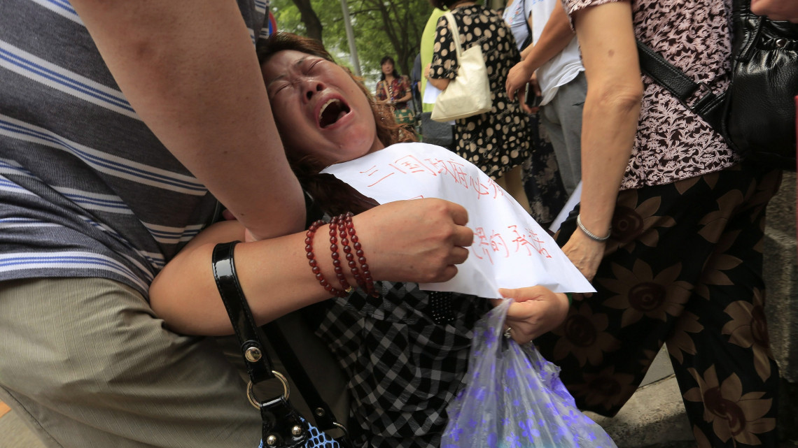 Peking, 2016. július 29.Az eltűnt maláj utasszállító repülőgép egyik utasának hozzátartozója sír egy plakáttal a kezében a külügyminisztérium épülete előtt tartott tüntetésen, Pekingben 2016. július 29-én. Egy héttel korábban a miniszterelnöki hivatal bejelentette, hogy felfüggesztik a Malaysia Airlines MH370-es járata utáni keresést. A Kuala Lumpurból Pekingbe tartó utasszállító gép 2014. március 8-án tűnt el, 239 emberrel a fedélzetén. (MTI/EPA/Ho Hvi Jung)