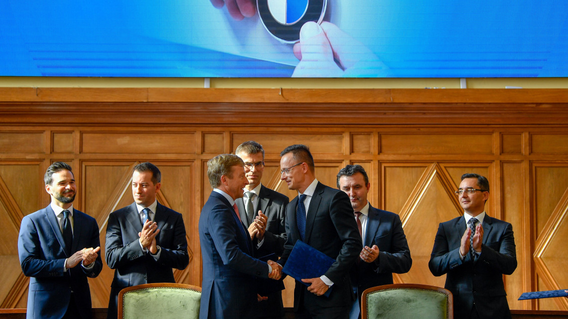 Oliver Zipse, a BMW Group igazgatótanácsának gyártásért felelős tagja (elöl b) és Szijjártó Péter külgazdasági és külügyminiszter (elöl j) kezet fog, miután aláírták a BMW debreceni gyárberuházásának támogatásáról szóló megállapodást a Debreceni Egyetemen 2018. október 12-én. Mögöttük Barcsa Lajos (Fidesz-KDNP) alpolgármester, Ésik Róbert, a Nemzeti Befektetési Ügynökség (HIPA) elnöke, Michele Melchiorre, a BMW gyár debreceni igazgatója, Palkovics László innovációs és technológiai miniszter és Papp László (Fidesz-KDNP) polgármester (b-j).