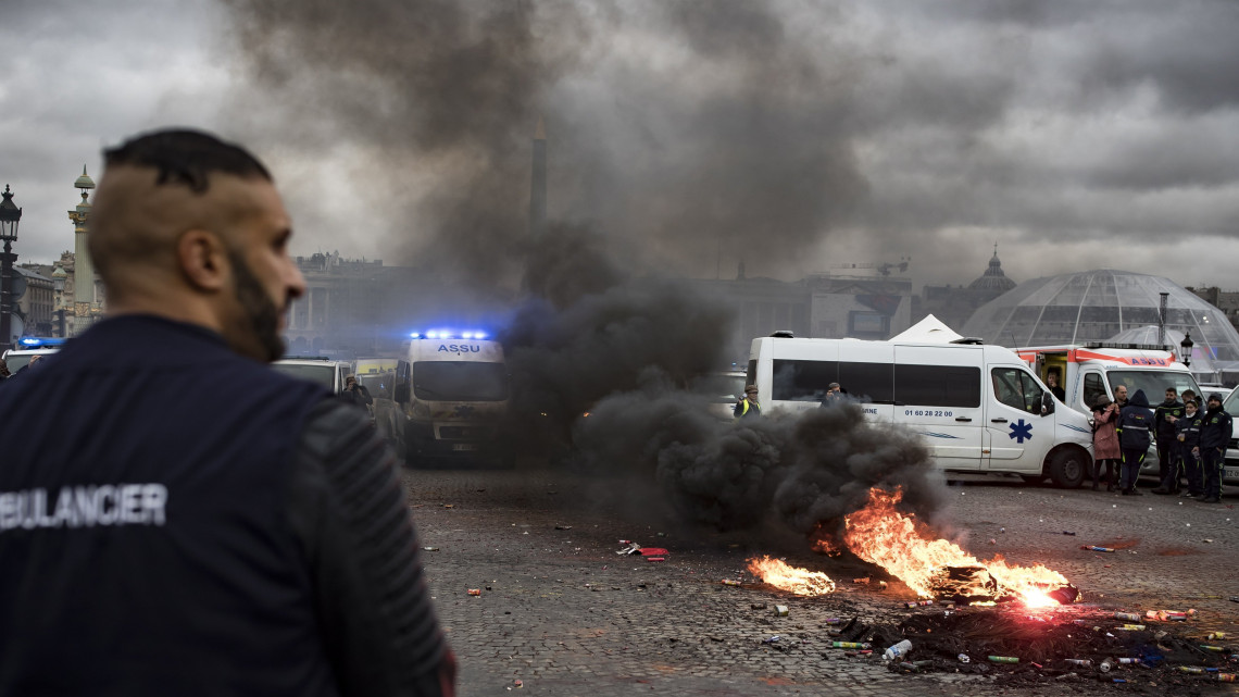 Felgyújtott kukáknál tüntetnek francia mentősök a munkakörülményeik javításáért a párizsi Concorde téren 2018. december 3-án. Emmanuel Macron francia elnök párbeszédre szólította fel Édouard Philippe miniszterelnököt a parlamenti pártok vezetőivel és a tüntetők képviselőivel a  láthatósági mellény viselése után sárgamellényesnek nevezett  megmozdulásokat kísérő zavargások nyomán kialakult válság felszámolására.