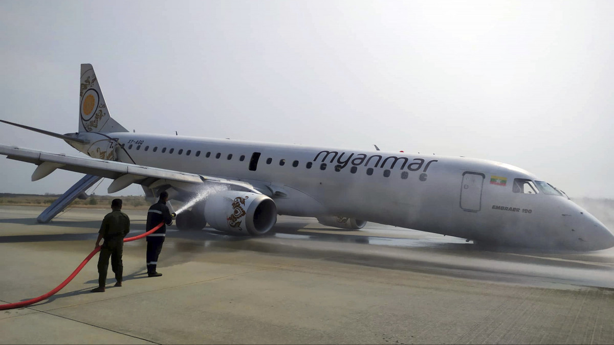 Tűzoltók locsolják a Myanmar Airlines légitársaság Embraer 190-LR típusú gépét, amelyet pilótája a futómű meghibásodása miatt az első kerekek nélkül tett le a mandalayi repülőtéren 2019. május 12-én. A gépen utazó 89 ember közül senki sem sérült meg.