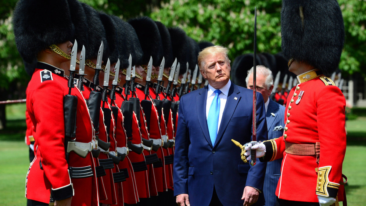 A brit védelmi minisztérium által közreadott felvételen Donald Trump amerikai elnök (k) ellép a tiszteletére felsorakozott díszegység előtt a londoni uralkodói rezidencia, a Buckingham-palota kertjében tartott fogadási ünnepségen 2019. június 3-án. Trump háromnapos állami látogatásra érkezett Nagy-Britanniába. Mögötte Károly walesi herceg, brit trónörökös.