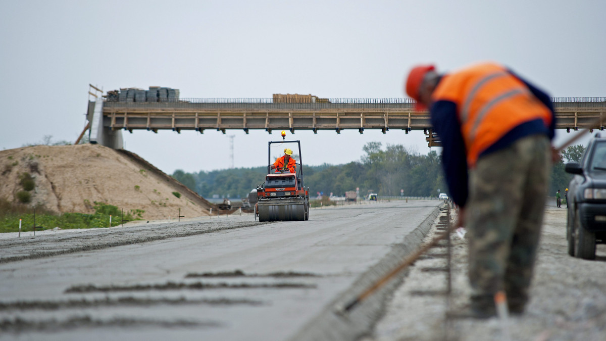 Útépítő munkások dolgoznak az M85-ös gyorsforgalmi út Enese - Csorna között épülő szakaszán, Győr közelében 2014. szeptember 25-én. A Nemzeti Infrastruktúra Fejlesztő Zrt. 450 milliárd forintos infrastrukturális programjának részeként valósul meg az M85 gyorsforgalmi út kiépítése. Az M85-ös gyorsforgalmi út Győr-Csorna közötti, 38 kilométer hosszú, 2x2 sávos szakasza, amely új nyomvonalon épül, 2015 nyarára készül el.