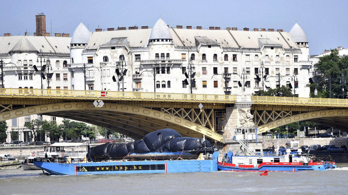 Budapest, 2019. június 13.
Uszály szállítja a balesetben elsüllyedt Hableány turistahajó roncsát az újpesti kikötőbe, középen a Margit híd 2019. június 13-án. A BRFK munkatársai huszonhat órán át vizsgálták a csepeli kikötőben a Dunából június 11-én kiemelt hajót, amely május 29-én süllyedt el a Margit hídnál, miután összeütközött a Viking Sigyn szállodahajóval. A Hableány fedélzetén 35-en utaztak, 33 dél-koreai állampolgár és a kéttagú magyar személyzet. Hét embert sikerült kimenteni, hét dél-koreai állampolgár holttestét pedig még aznap megtalálták. Továbbra is a Duna teljes déli szakaszán, az összes bevethető hajóval, valamint parti egységekkel megerősítve folytatják a hiányzó három ember keresését.
MTI/Illyés Tibor