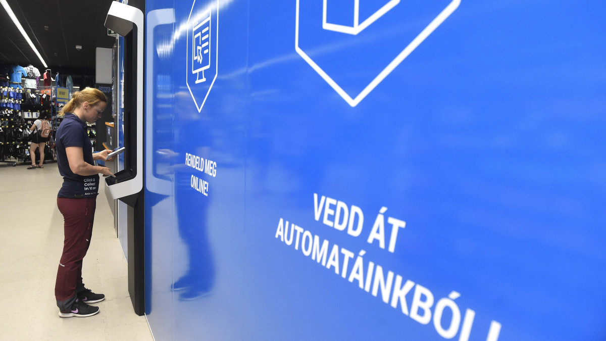 Robot vezérelte csomagkiadó automatából veszi ki a megrendelt terméket egy vevő a Decathlon budapesti Nyugati téri sportáruházában 2019. június 26-án.