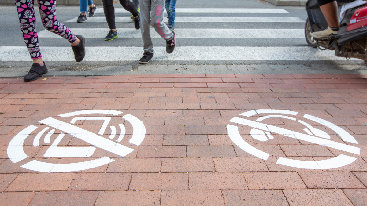 A mobiltelefonos balesetek megelőzésének céljából járdára festett piktogramok egy gyalogos átkelőhelynél Orosházán 2019. október 4-én. Az önkormányzat megbízásából huszonöt zebránál festettek piktogramokat, amelyek arra figyelmeztetik a zebrán áthaladókat, hogy közben ne használjanak mobiltelefont, fülhallgatót, vagy bármilyen olyan eszközt, ami elvonja a figyelmüket a biztonságos közlekedésről.