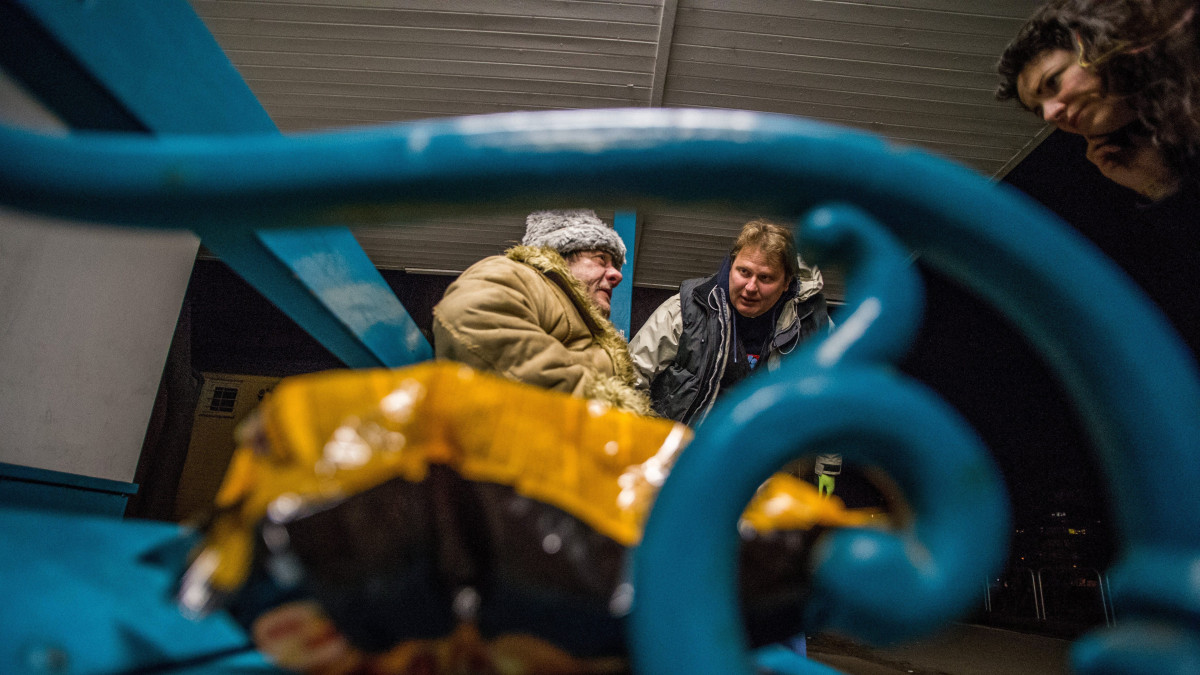 Az otthontalanokat segítő Menhely Alapítvány 24 órában működő krízisautó szolgálatának munkatársai hajléktalan férfinak segítenek a főváros XV. kerületében, a MÁV-telep villamosmegállónál 2018. február 25-én. Az alapítvány munkatársai a hideg idő miatt a nappali melegedőbe és az éjjeli menedékhelyre próbálják eljuttatni az utcán élőket.