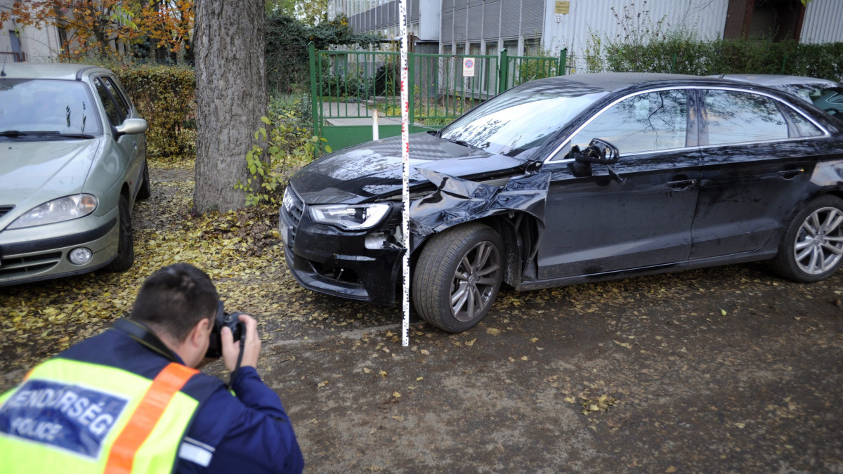 Rendőr helyszínel egy összetört személyautó mellett a XIV. kerületi Nagy Lajos király útján 2016. november 7-én, miután az autó eddig tisztázatlan körülmények halálra gázolt egy idős férfit a Füredi utcában.