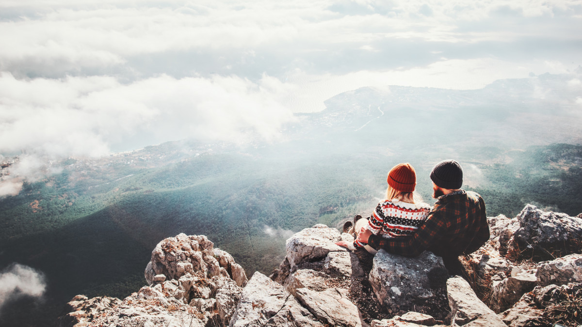 Couple travelers Man and Woman sitting on cliff relaxing mountains and clouds aerial view  Love and Travel happy emotions Lifestyle concept. Young family traveling active adventure vacations