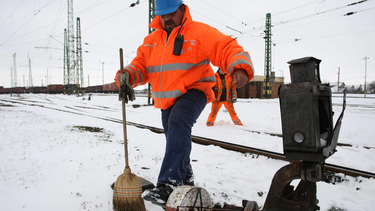 A helyi állomásfőnökség tolatásvezetője ellenőrzi egy megtisztított váltóberendezés működőképességét a szolnoki vasútállomás területén 2013. március 26-án. A rendkívüli időjárás miatt a MÁV szakemberei megerősített szolgálatban dolgoznak, országszerte összesen 600 ember végzi a váltók hó- és fagymentesítését.