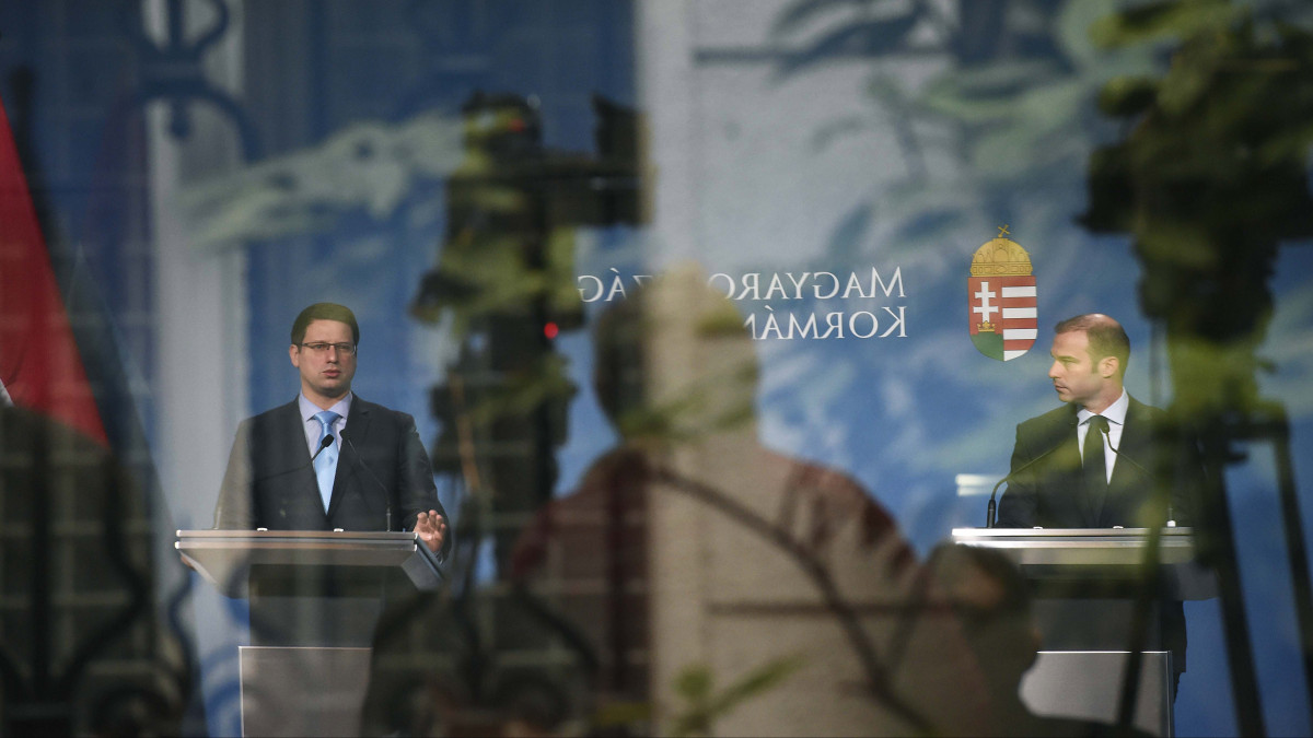 Az üvegfelületen tükröződő képen Gulyás Gergely Miniszterelnökséget vezető miniszter (b) és Hollik István kormányszóvivő a Kormányinfó sajtótájékoztatón a Miniszterelnöki Kabinetiroda Garibaldi utcai sajtótermében 2019. december 19-én.