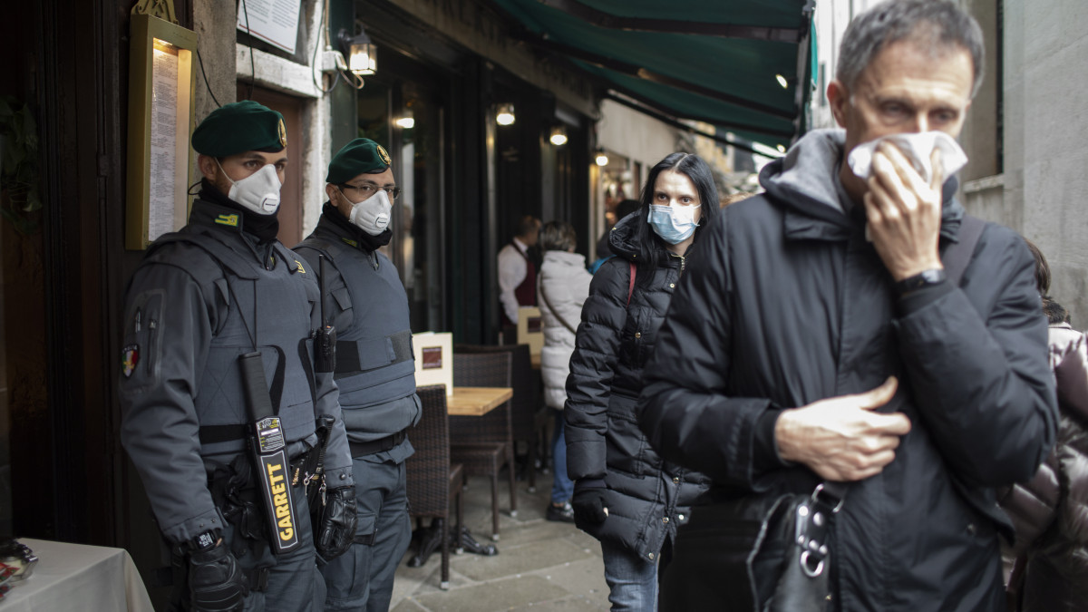 A koronavírus elleni védekezésül szájmaszkot viselő rendőrök és turisták a velencei karneválon a Szent Márk tér közelében 2020. február 23-án. Luca Zaia, az északkelet-olaszországi Veneto tartomány kormányzója ezen a napon bejelentette, hogy a koronavírus-járvány olaszországi terjedése miatt megszakítják a velencei karnevált. A tüdőgyulladást okozó, Covid-19-nek elnevezett újfajta koronavírus fertőzöttjeinek száma 115 fölé emelkedett Olaszországban.