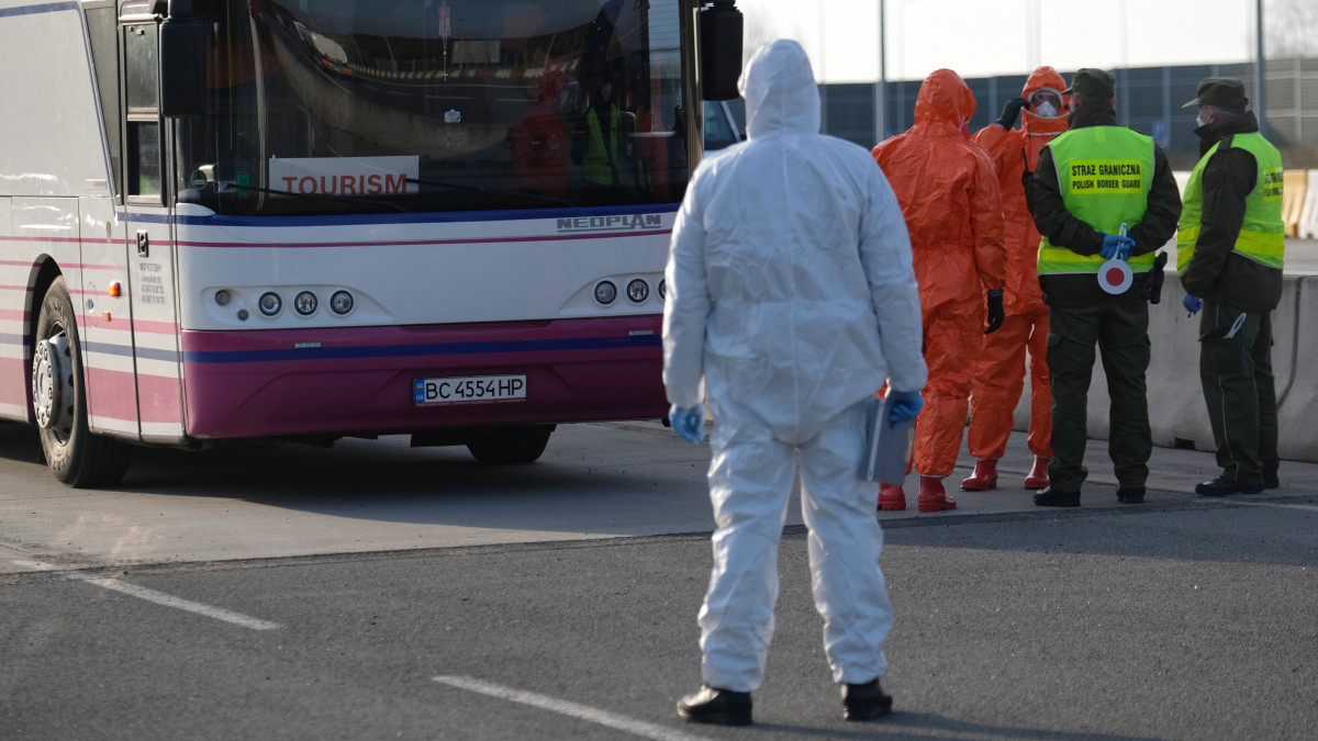 Lengyel határőrök védőfelszerelésben ellenőrzik az ország területére belépő busz utasait a cseh határnál fekvő Gorzyczkiben 2020. március 9-én. Mateusz Morawiecki kormányfő bejelentette, hogy Lengyelország összes közúti, vasúti határátkelőhelyén, valamint a balti-tengeri kikötőkben is egészségügyi ellenőrzést vezetnek be.