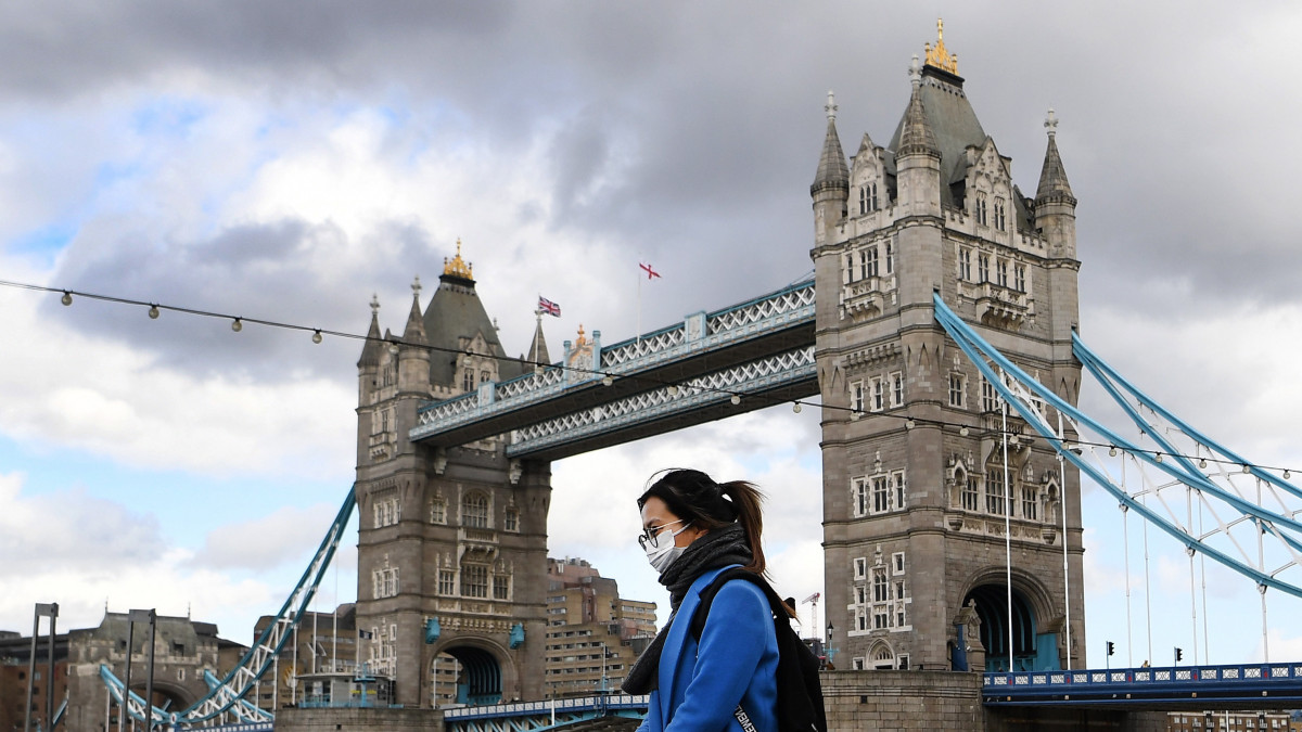 Védőmaszkot viselő gyalogos a londoni Tower Bridge előtt 2020. március 12-én. Nagy-Britanniában tízre emelkedett a tüdőgyulladást okozó koronavírus halálos áldozatainak száma.