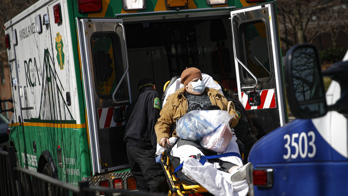 Védőmaszkos beteget tesznek mentőautóba a New York-i Brooklyn Kórházközpontnál 2020. március 18-án. Az új koronavírus járványának súlyosbodására készülve ágyakat szabadítanak fel az amerikai nagyváros kórházaiban.