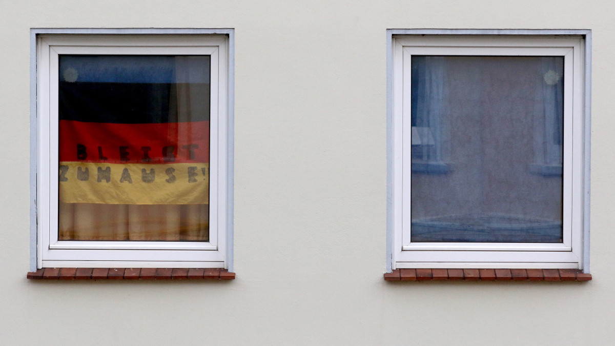 Az új koronavírus járványa miatt a Maradj otthon! felirat olvasható egy lakás ablakába helyezett nemzeti színű zászlón Brémában 2020. március 20-án. Németországban eddig 17742 fertőzött személyt regisztráltak, a halálos áldozatok száma 48-ra emelkedett.