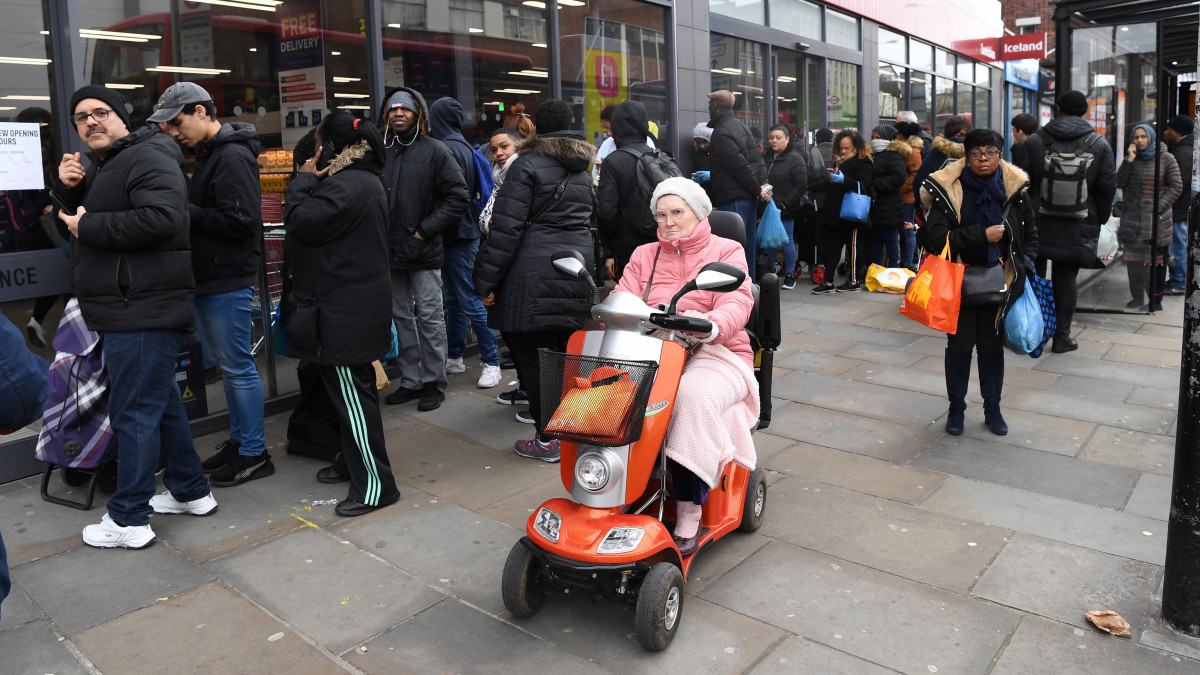 Sorban állnak a vásárlók egy dél-londoni ABC-áruház előtt 2020. március 20-án. A brit kormány felhívta az emberek figyelmét, hogy aki az új koronavírusra jellemző tüneteket észleli magán, vagy hozzátartozójának vannak ilyen tünetei, családtagjaival együtt 14 napig ne hagyja el az otthonát.