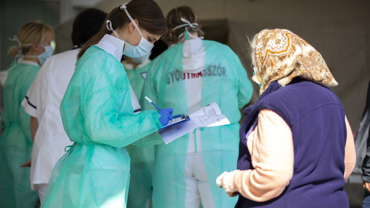 Vizsgálatra érkező nővel beszélget egy védőmaszkot viselő nővér Nagykanizsán, a Kanizsai Dorottya Kórház előtt 2020. március 20-án. A koronavírus-járvány miatt az intézmény előtt szűrősátrakat állítottak fel és bevezették az egykapus beléptetést.
