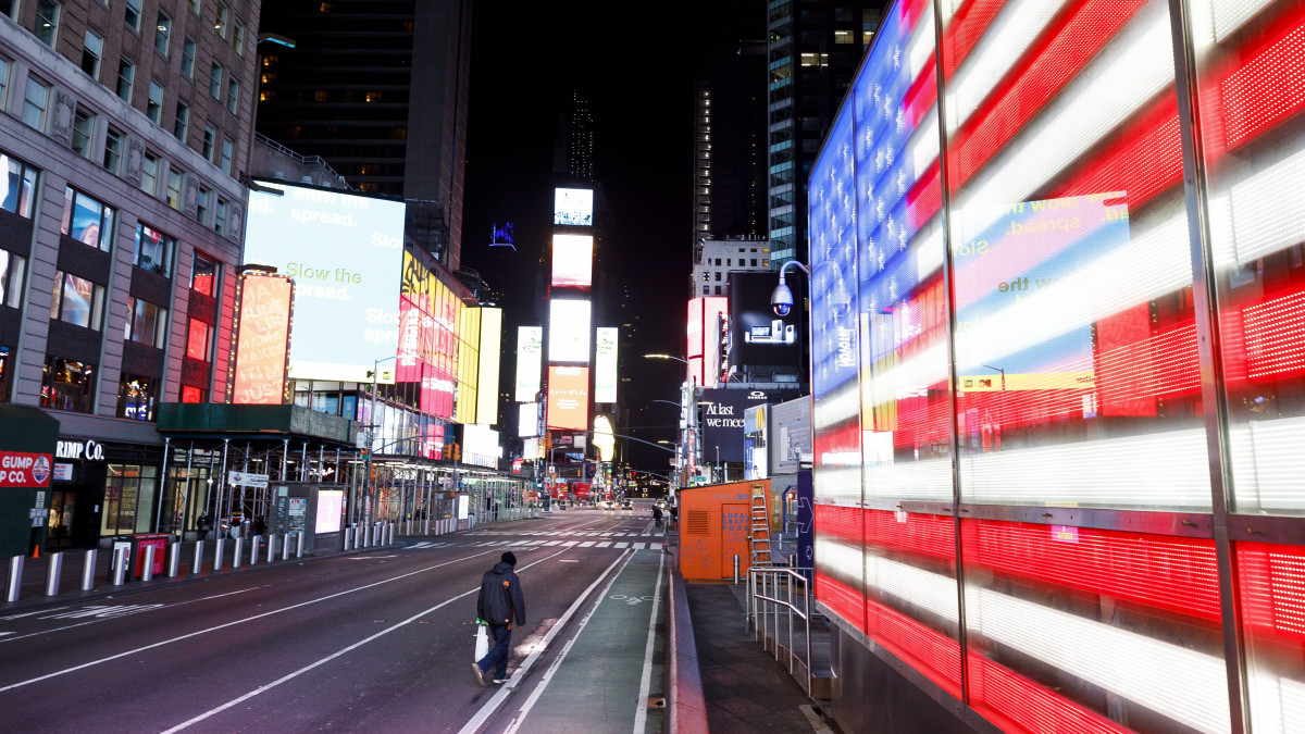 Férfi sétál át az elnéptelenedett New York-i Times Square-en 2020. március 26-án. A koronavírus-járvány terjedésének megakadályozására New York állam kormányzója elrendelte a vendéglátóhelyek, mozik, szórakozóhelyek zárva tartását, az éttermek csak elvitelre és házhozszállítással szolgálhatják ki a vásárlókat. Donald Trump amerikai elnök előző nap azt nyilatkozta, hogy a New York államban kialakult járványhelyzet a legsúlyosabb az Egyesült Államokban.