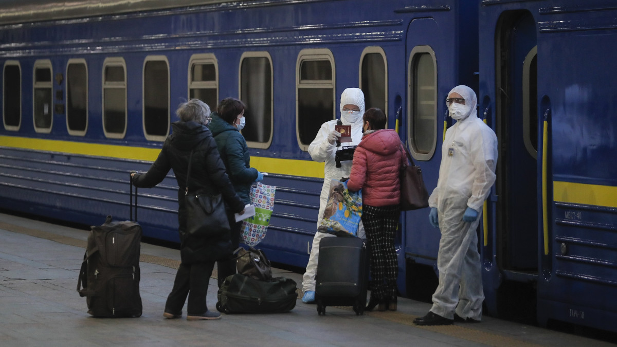 Védőruházatot viselő munkások ellenőrzik utasok iratait a kijevi vasútállomáson 2020. március 27-én. Az ukrán kormány bejelentette, hogy a koronavírus-járvány miatt Ukrajna teljesen leállítja a nemzetközi utasszállítást, azaz lezárja határait saját állampolgárai előtt is. Az orosz állami vasúti társaság különvonatot indít az orosz állampolgárok Ukrajnából és az ukránok Oroszországból történő hazaszállítására. A mintegy 800 férőhelyes szerelvény a tervek szerint 27-én indul Kijevből és másnap érkezik meg Moszkvába.