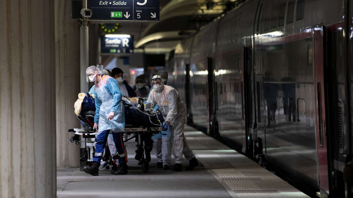 Az új koronavírussal fertőzött beteget visznek egy TGV szuperexpresszvonathoz a párizsi Austerlitz pályaudvaron 2020. április 1-jén. Két szerelvénnyel 36 beteget szállítanak el a fővárosból a nyugat-franciaországi Bretagne kórházaiba.