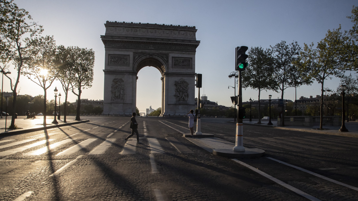 A párizsi Champs Elysées sugárúton, a diadalív előtt kel át egy járókelő a koronavírus-járvány idején, 2020. április 14-én.