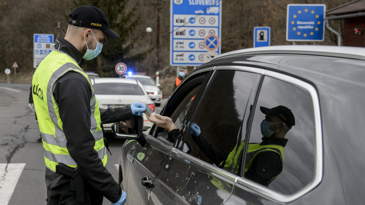 Szlovák rendőr egy autós iratait ellenőrzi a Somoskőújfalui és Sátorosbánya közötti határátkelőhelyen 2020. március 13-án. A koronavírus terjedésének megakadályozása érdekében a szlovák kormány reggel 7 órától a közúti határátkelőin - a lengyel határszakaszt kivéve - visszaállítja a határellenőrzést. Csak azokat engedik be Szlovákiába, akik szlovák állampolgárok, és akiknek az országban tartózkodási engedélyük van. Minden külföldről érkezőnek 14 napos karanténba kell vonulnia.