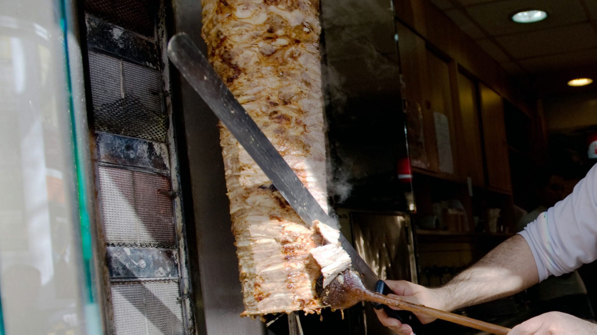 Gyros húst vág az egyik tulajdonos egy török étterem, utcára nyíló kiszolgáló ablakában az Erzsébet körúton.