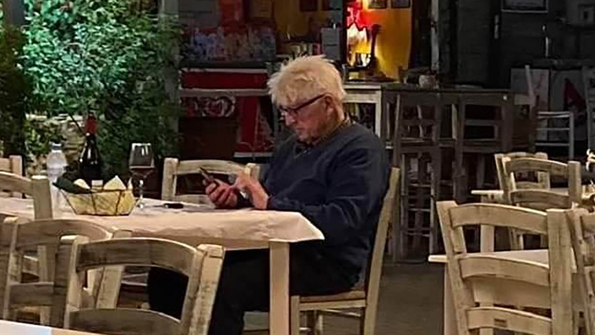 Stanley Johnson, Boris Johnson brit miniszterelnök apja a telefonját nézi a görögországi Horto falu egyik éttermében 2020. július 2-án. A brit államfő apja július 3-án érkezett Athénba Bulgárián keresztül, miután Nagy-Britanniából a koronavírus-járvány miatt nem indulnak közvetlen repülőjáratok.