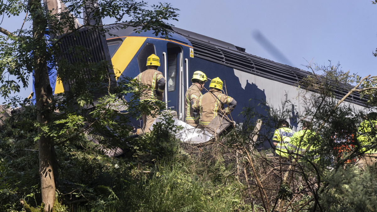 Mentők és rendőrök dolgoznak egy kisiklott vonat körül a skóciai Stonehaven közelében, Aberdeentől délre 2020. augusztus 12-én. A sérültek és halottak számáról egyelőre nincs hivatalos közlés, Nicola Sturgeon skót kormányfő azonban a Twitteren azt írta, hogy rendkívül súlyos baleset történt. A környéken heves esőzések voltak a balesetet megelőzően.