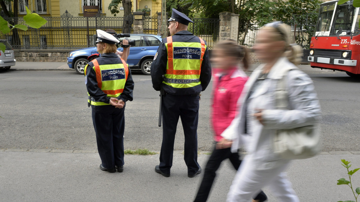 Rendőrök állnak Az iskola rendőre elnevezésű programban részt vevő Városligeti Magyar-Angol Két Tanítási Nyelvű Általános Iskola előtt Budapesten 2013. szeptember 2-án. A 2013/14-es tanévben mintegy 2800 oktatási intézmény kapcsolódott be a közbiztonságot növelő programba, amelyben több mint 2200 rendőr vesz részt.