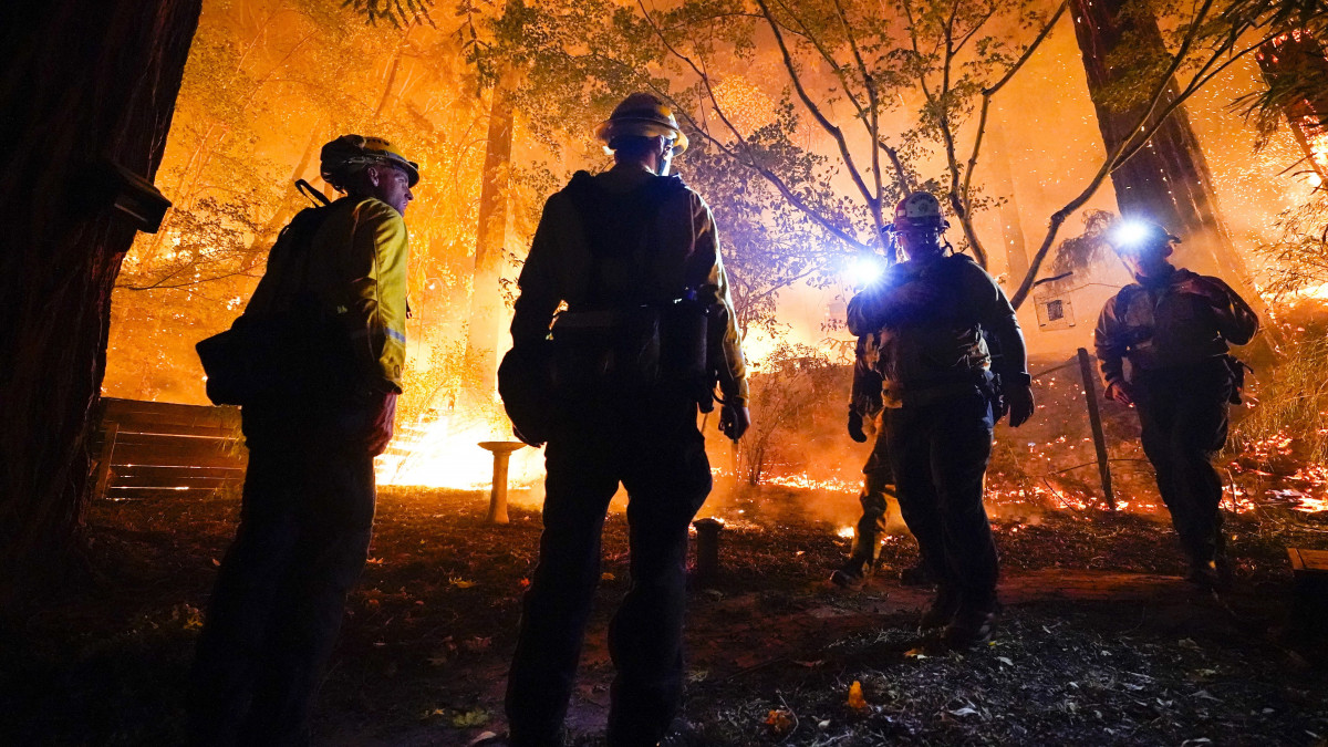 Egy Boulder Creek-i ház hátsó kertjében gyújtott ellentűz lángjait figyelik tűzoltók, miközben a település felé erdőtűz közelít 2020. augusztus 21-én. A Kaliforniában pusztító bozóttüzek miatt mintegy 120 ezer embernek kellett elhagynia otthonát, hatan életüket vesztették.