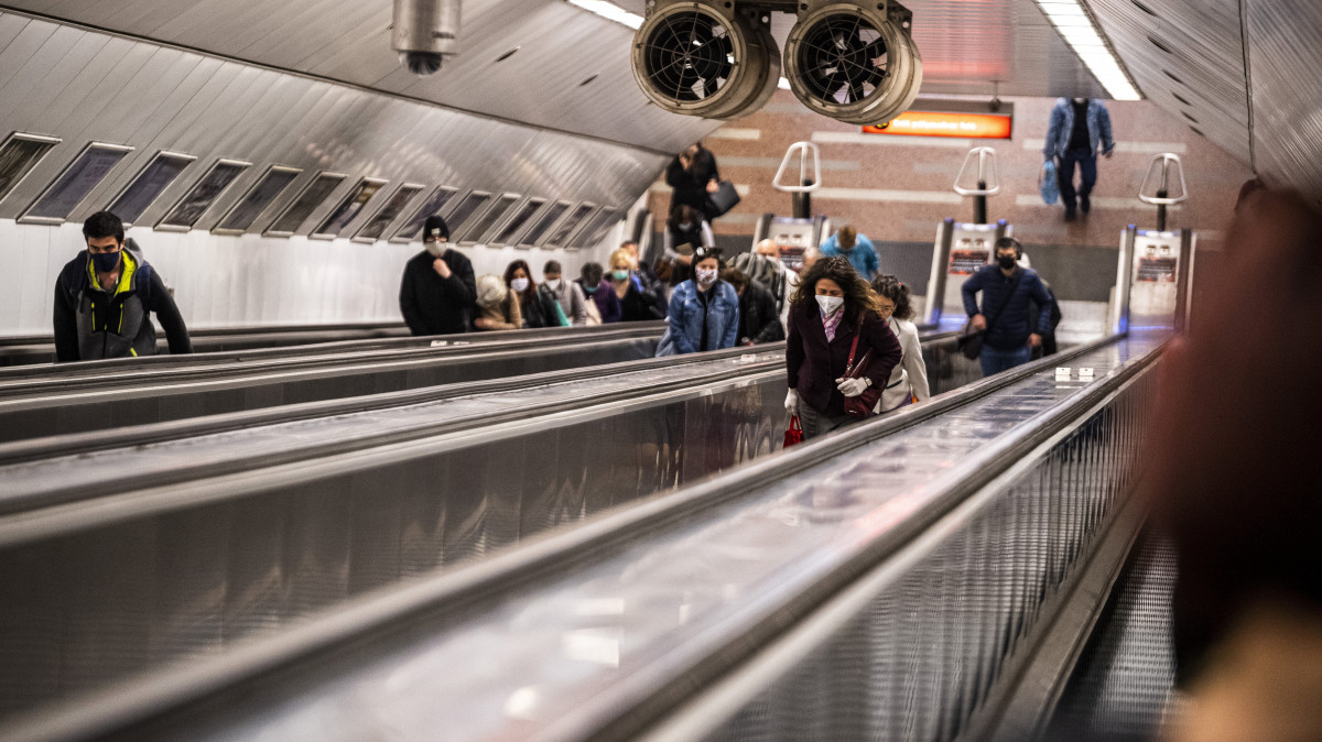 Védőmaszkot viselő utasok a Széll Kálmán téri metróálllomás mozgólépcsőjén 2020. április 27-én. Ettől a naptól csak sállal, kendővel vagy maszkkal eltakart arccal szabad felszállni a fővárosi tömegközlekedés járataira, s így lehet csak boltba menni és taxival utazni a koronavírus-járvány terjedésének megakadályozása érdekében. Az intézkedés nem vonatkozik a 6 éven aluli utasokra. A rendelkezés betartásának elősegítése érdekében a Budapesti Közlekedési Központ (BKK) és a Főpolgármesteri Hivatal több csomópontban mosható és vasalható textilmaszkot oszt az utazóknak.