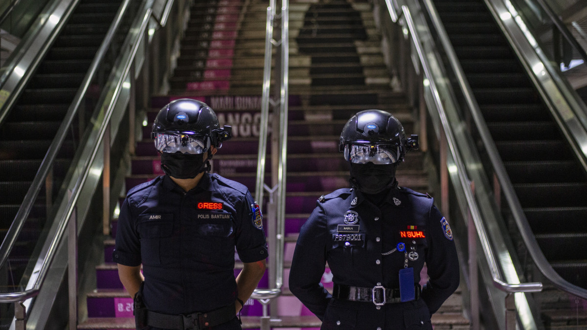 A KTMB maláj vasúttársaság biztonsági őrei az utasok testhőmérsékletének mérésére alkalmas okossisakkal egy Kuala Lumpur-i vasútállomáson 2020. október 14-én. A koronavírus-járvány terjedése miatta a malajziai kormány az ország egyes területein szigorította a biztonsági intézkedéseket.