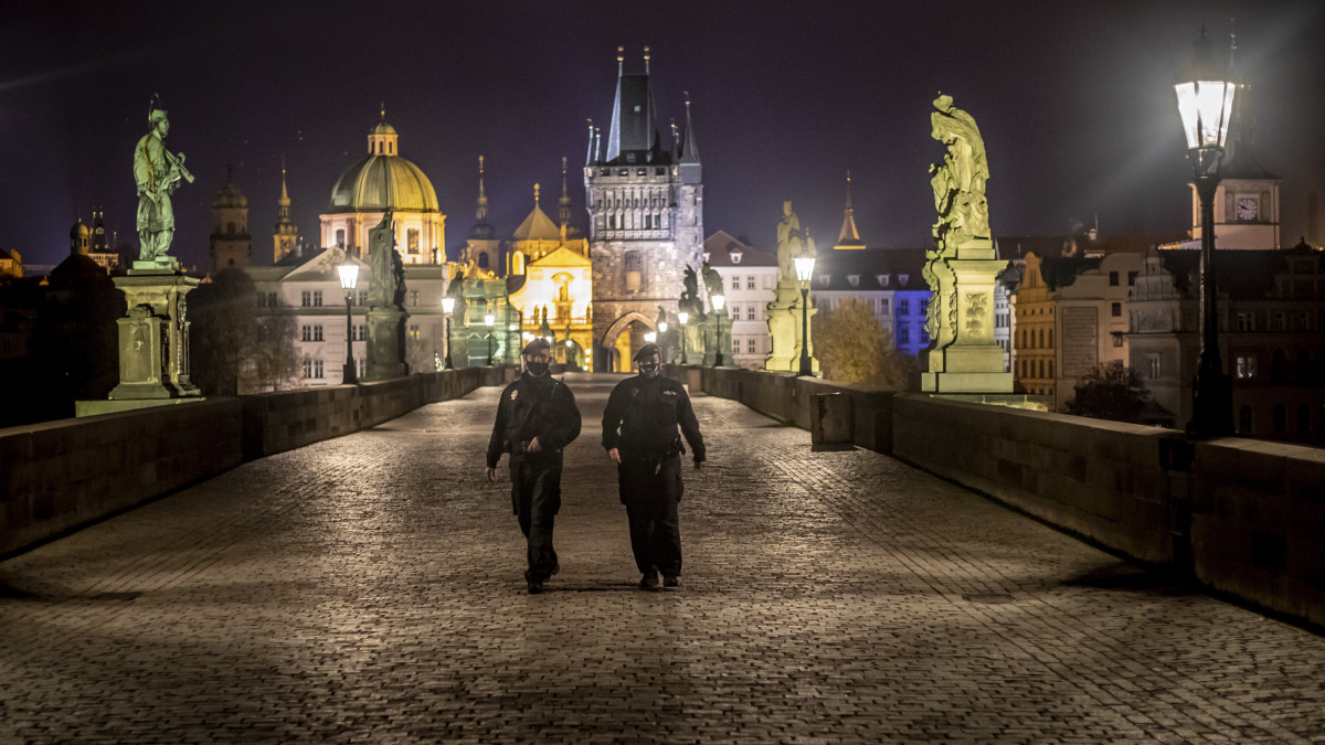 Járőröző rendőrök a prágai Károly hídon 2020. október 28-án. A koronavírus-járvány megfékezése miatt elrendelt kijárási tilalom ezen a napon lépett életbe Csehországban. A kormányrendelet szerint este kilenc órától reggel ötig a csehek csak bizonyos kivételekkel - egyebek között a munkahelyre való utazás vagy egészségi probléma - hagyhatják el lakhelyüket.